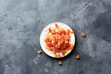 Cubes of dried apricot, mango and papaya on white palte. Candied fruits over gray background with copy space. Top view.の写真素材