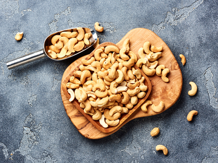 Roasted cashew nuts and scoop on gray background. Top view.の写真素材