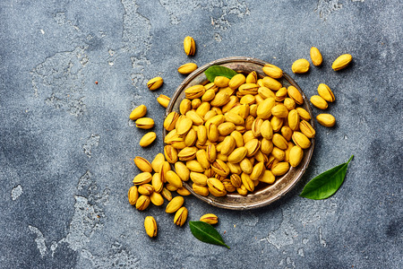 Yellow pistachios spiced with turmeric on gray background. Top view of nuts.の写真素材