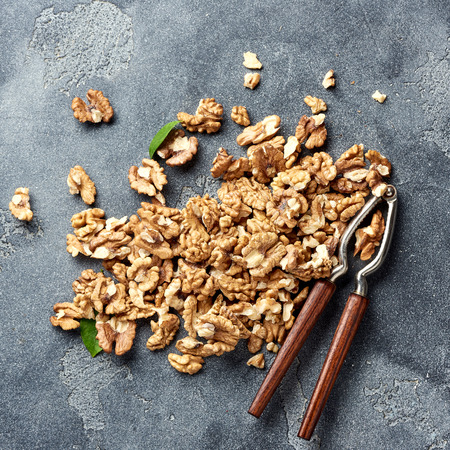 Walnut kernels and nutcracker. Nuts with green leaves. Top view.の写真素材