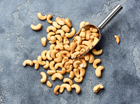 Roasted cashew nuts and scoop on gray background. Top view.の写真素材