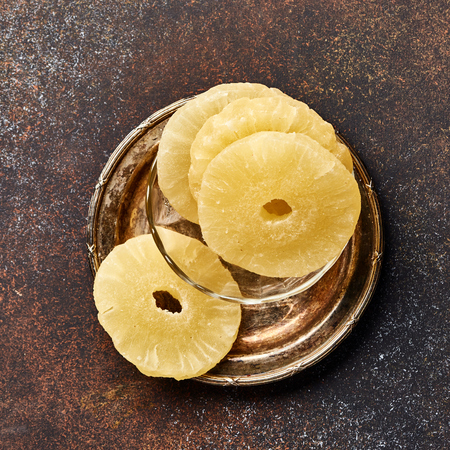 Dried pineapple rings on a brown table. Top viw of sweet paneapple slices.の写真素材
