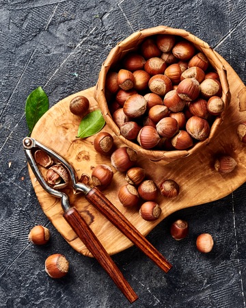 Hazelnut with nutcracker on olive wooden board. Nuts with green leaves. Top view.の写真素材