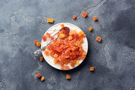 Cubes of dried apricot, mango and papaya on white palte. Candied fruits over gray background with copy space. Top view.の写真素材