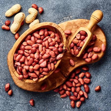 Peeled peanuts in bowl and scoop on gray background. Top view of nuts.の写真素材
