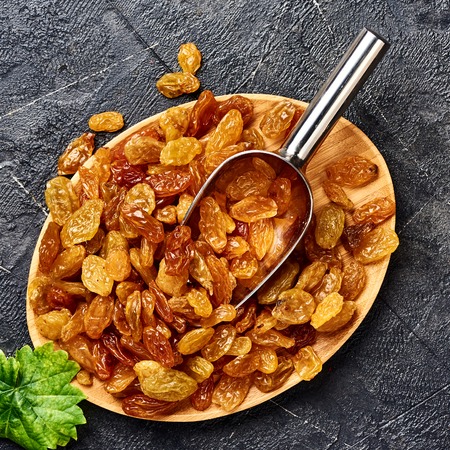 Yellow big raisins on gray concrete background. Top view of dried grapes.の写真素材