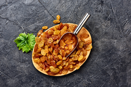 Yellow big raisins on gray concrete background with copy space. Top view of dried grapes.の写真素材