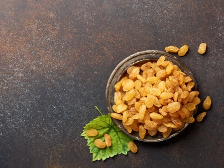Heap of yellow raisins. Top view of dried grapes with green leaf.の写真素材