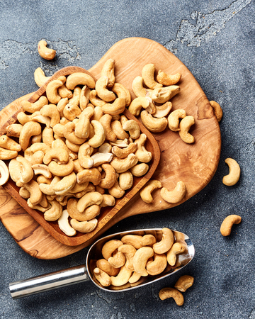 Roasted cashew nuts and scoop on gray background. Top view.の写真素材