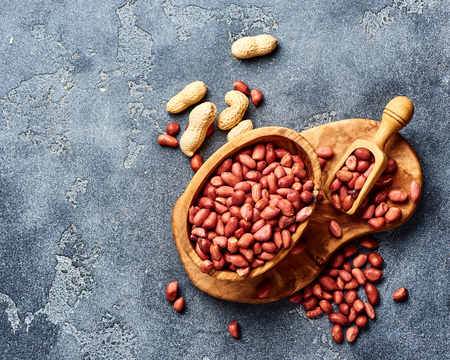 Peeled peanuts in bowl and scoop on gray background. Top view of nuts.の写真素材