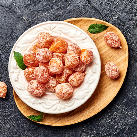 Dried sweet kumquat under powdered sugar on plate. Top view of dessert.の写真素材