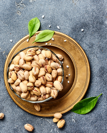 Salted Pistachios with green leaves. Top view of snacks.の写真素材