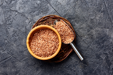 Wild brown rice in wooden bowl on black background. Top view of grains.の写真素材