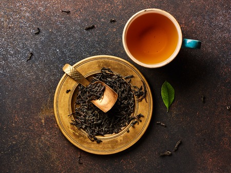 Top view of dried black tea and cup on brown background.の写真素材