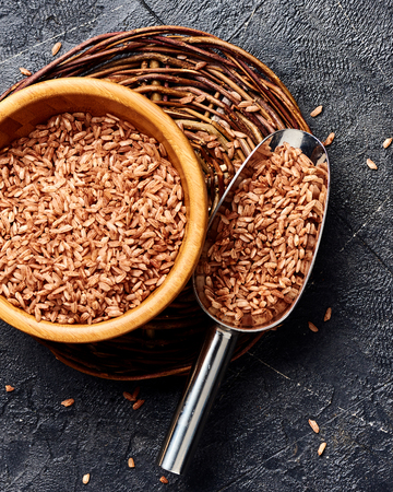 Wild brown rice in wooden bowl on black background. Top view of grains.の写真素材