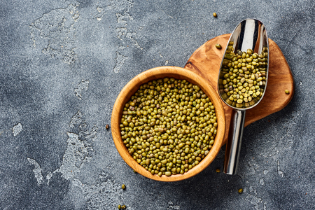 Green mung beans in wooden bowl on gray table. Top view of groats.の写真素材