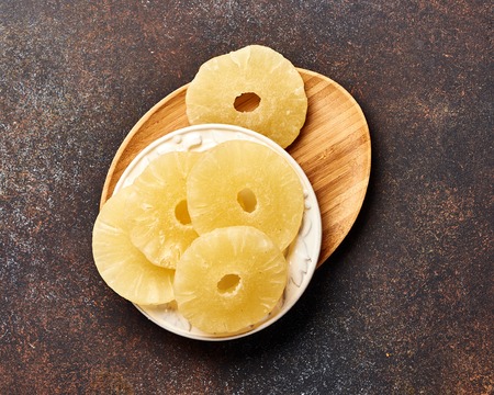Dried pineapple rings on a brown table. Top viw of sweet paneapple slices.の写真素材