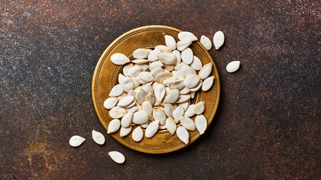 Raw pumpkins seeds on brown background with copy space. Top view.の写真素材