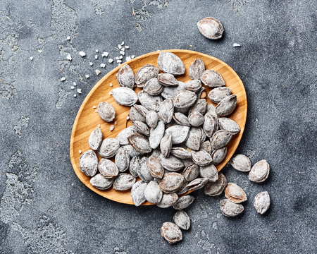 Salted apricot seeds on grey background. Apricot bones fried with salt in ashes.の写真素材