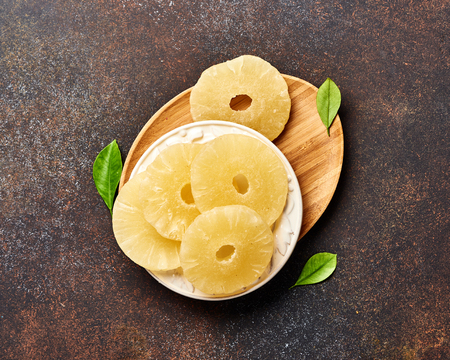 Dried pineapple rings on a brown table. Top view of sweet pineapple slices.の写真素材