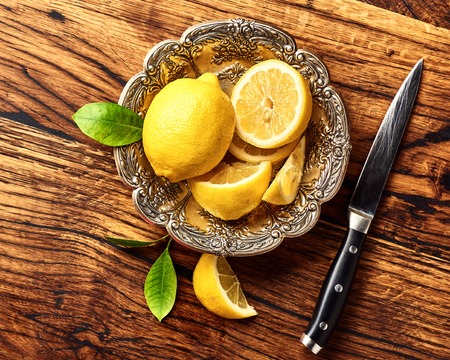Lemons with leaves on oak wooden table. Top view of fruits with knife.の写真素材