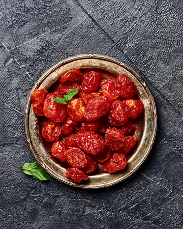 Candied cherry tomatoes on black background. Top view of dessert.の写真素材