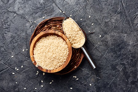 White rice in wooden bowl on black background. Top view of grains.の写真素材