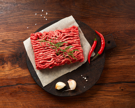 Minced beef meat with salt, garlic, herbs on wooden table. Top view.の写真素材