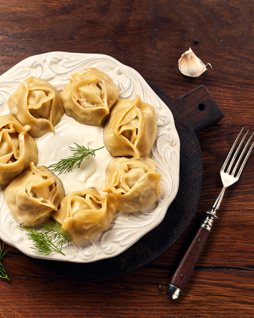 Asian steamed dumplings Manti with dill and garlic on wooden background.の写真素材