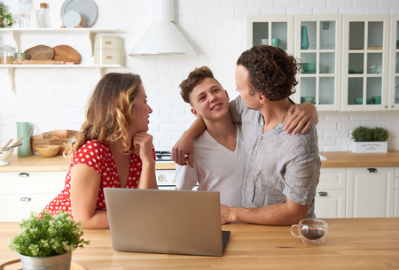 happy family with laptop at kitchen. Son, mother and father together.の写真素材