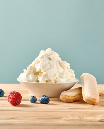 Mascarpone cheese, savoiardi biscuits and berries on wooden table. Homemade cream cheese.の写真素材