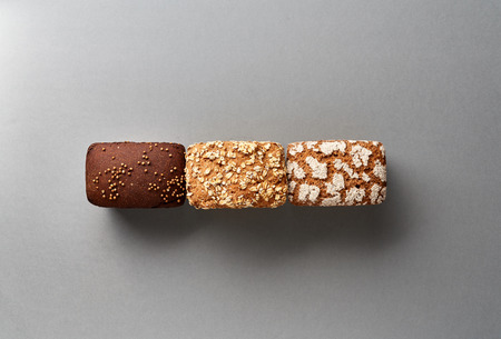 Three loaves of bread on gray background. Bakery concept with empty space for design. Gluten-free rye bread with bran and corianderの写真素材