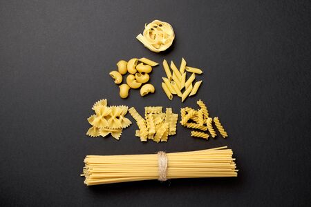 A christmas tree made with various forms of pasta on black background. Top view. Copy space for text. Concept.の写真素材