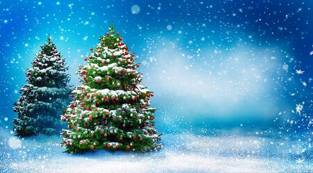 Beautiful snowy Christmas background with two New Year trees. Christmas tree decorated with red balls and snow. Winter landscape with snowfall.の写真素材