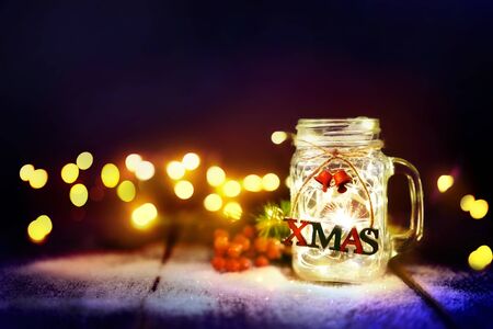Christmas lights in the glass jar with snow. Winter Christmas bokeh on the holiday card.の写真素材