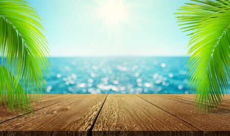Mockup of empty wooden table with palm branches on beautiful blur defocused blue sea background. Summer vacation conceptの写真素材
