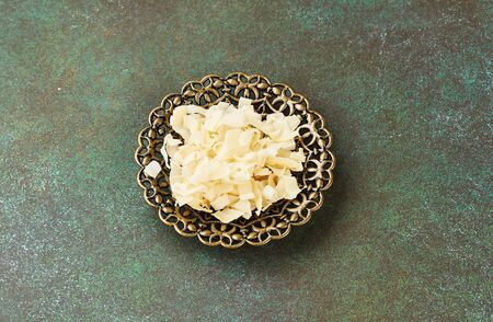 Organic Roasted coconut chips in a arabic bowl on a green background.の写真素材