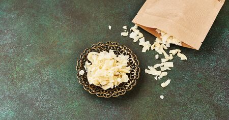 Organic Roasted coconut chips in a arabic bowl on a green background with paper package.の写真素材