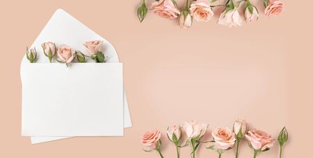 Blank envelope with rose flowers on peach color background. Top view of spring roses and rosebuds. Happy Mothers Day.の写真素材