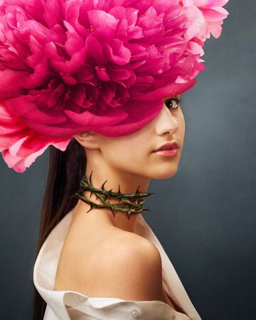 Surreal portrait of a girl with peonies flowers on head and rose thorns on the neck. In Ful Bloom. Interior photo art in art deco style. Beautiful surrealistic art picture. Mixed media.の写真素材