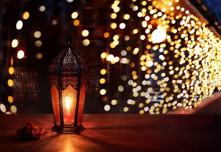 Ramadan lantern on the table. Dark background with light and bokehs. Beautiful Greeting Card with...