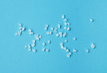 Sea salt granules isolated on blue background.の写真素材