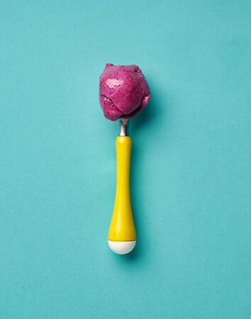 Ice cream spoon with berry ice cream on turquoise backgroundの写真素材