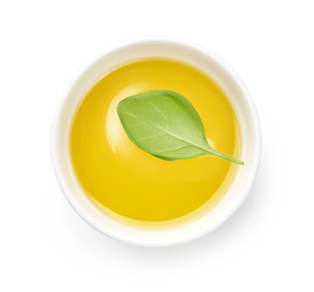 Olive or vegetable oil in white bowl. Top view of oil with basil leaf isolated on white background.の写真素材