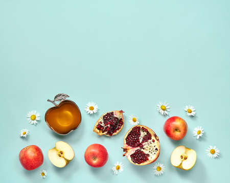Rosh hashanah (jewish New Year holiday) concept. Traditional symbols. Apples, honey and pomegranates on a light blue background.の写真素材