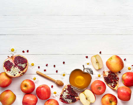 Rosh hashanah (jewish New Year holiday) concept. Traditional symbols. Apples, honey and pomegranates on a white wooden background.の写真素材