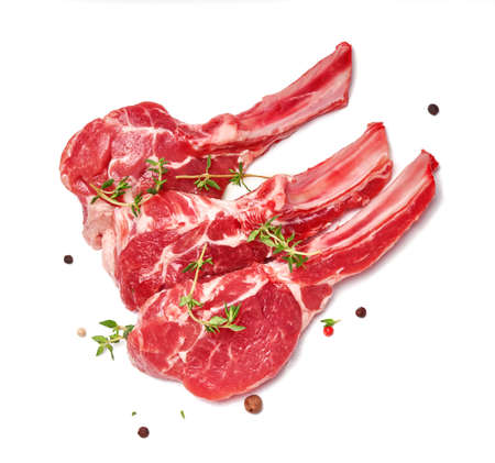 Three pieces of mutton meat with herbs and mixed peppers isolated on white background. Top view of mutton steaks with thyme herb.の写真素材