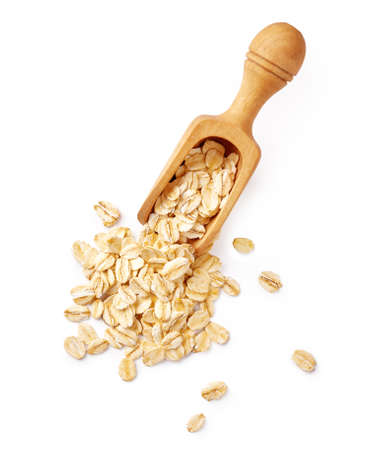 Oat flakes in wooden spoon isolated on white background. Top view of oat flakes for oatmeal and granola.の写真素材
