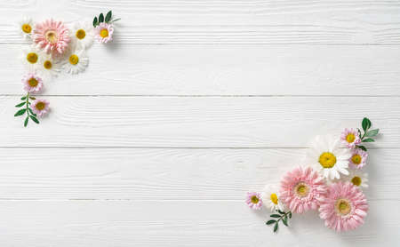 Flowers composition. White flowers on white wooden background. Wedding mockup with pink and white flowers. Flat lay, top view, frame. Gerbera, chamomile flowers.の写真素材