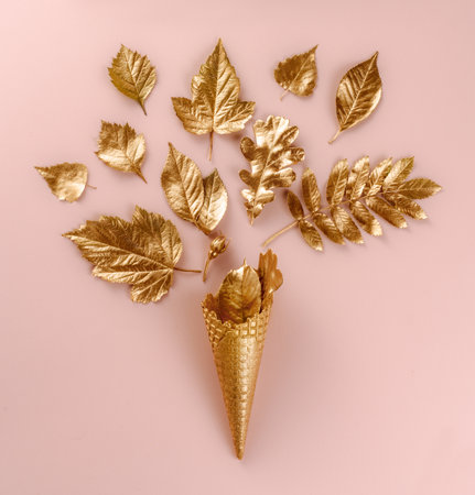 Wall Art. Botanical set. Lifestyle decoration. Gold ice cream cone with autumn gold leaves, on pink background. Flat lay. Top view. Beautiful composition with leaves in bright golden paintの写真素材